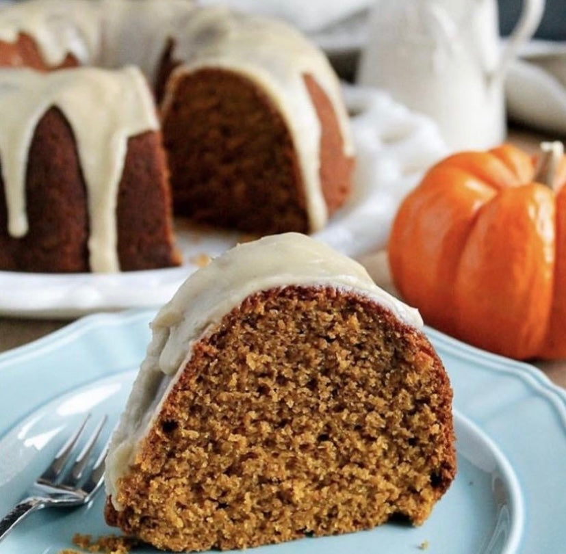 moist  pumpkin spice cake, topped with icing and nuts, resting on a dessert plate.